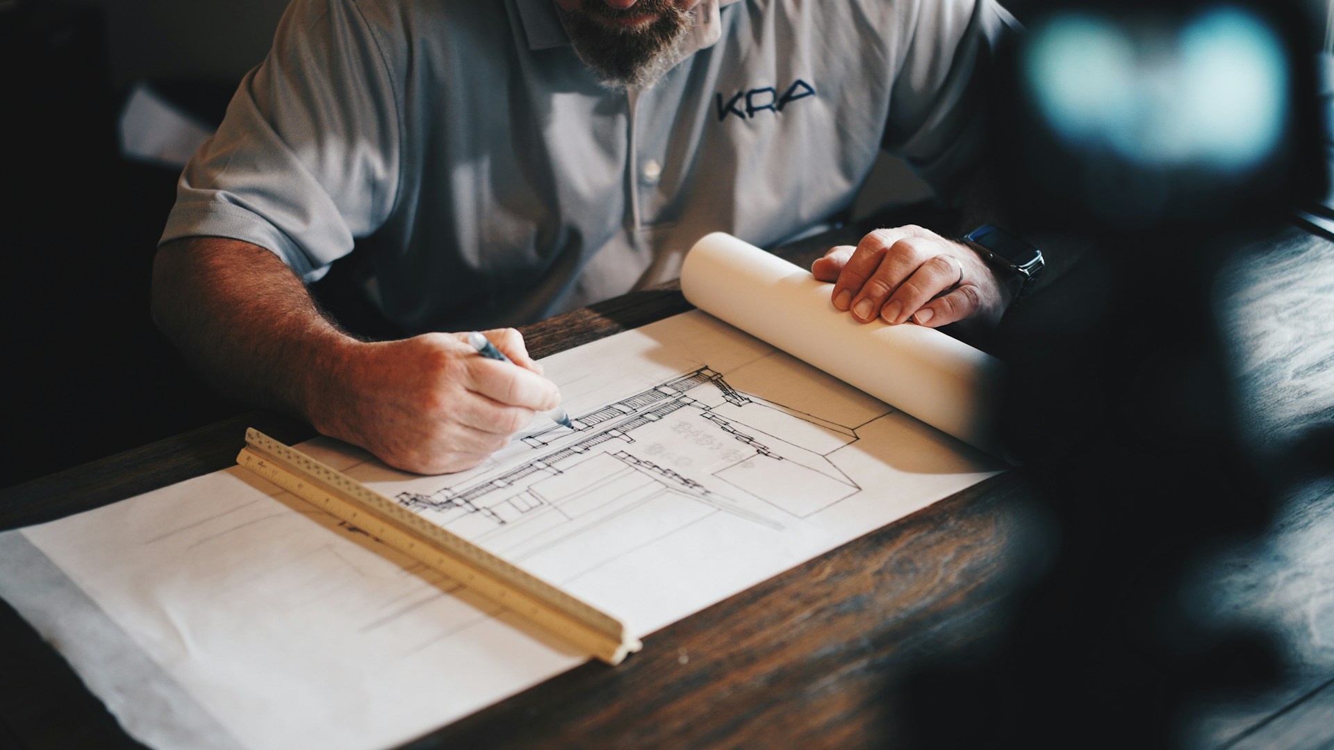 Builder sketching architectural plans at a desk