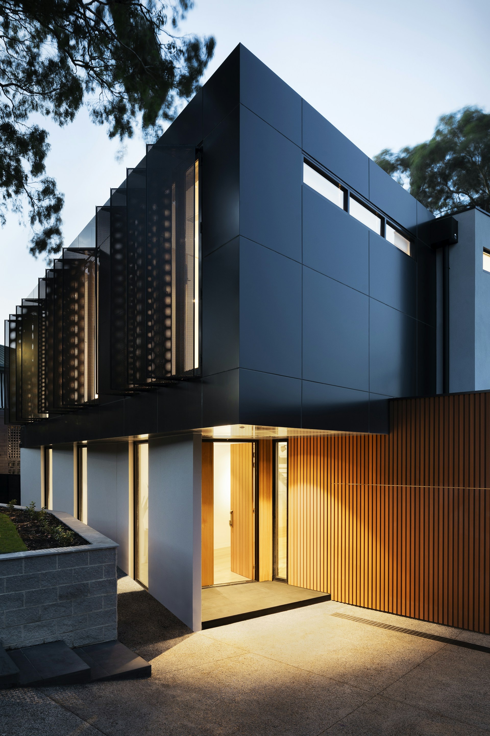 Contemporary house exterior with dark cladding and timber slat feature wall